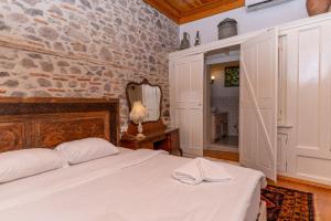 1 dormitorio con cama blanca y pared de piedra en Dutlu Konak, en Izmir