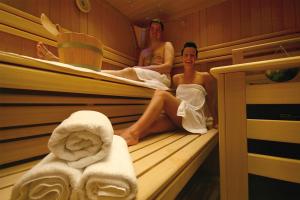 two women sitting in a sauna with towels at LandKomfort Hotel Elsenmann Garni in Willingen