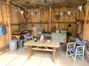 patio con mesa y sillas y cocina en Genuine Gypsy Hut and Glamping Experience - In the Heart of Cornwall, en Gunnislake