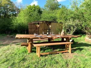 un tavolo da picnic in legno con una bottiglia di vino e 2 panche di Genuine Gypsy Hut and Glamping Experience - In the Heart of Cornwall a Gunnislake