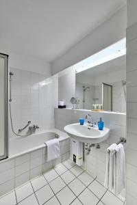 uma casa de banho branca com um lavatório e uma banheira em Hohe Worth - 211 em Cuxhaven