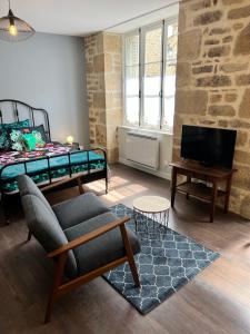 un soggiorno con letto, divano e TV di Treignac Place Studio a Treignac