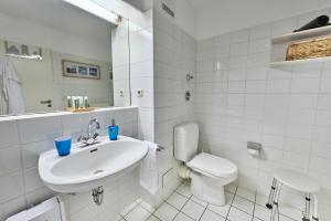 uma casa de banho branca com um lavatório e um WC em Hohe Worth - 211 em Cuxhaven