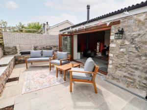 a patio with chairs and a table and a stone wall at Lime Kiln Cottage in Bridgend