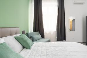 een slaapkamer met een wit bed en een stoel bij Le Cinque Stanze Palermo Room&Breakfast in Palermo