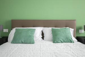 1 cama con paredes verdes y 2 almohadas verdes en Le Cinque Stanze Palermo Room&Breakfast, en Palermo
