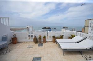 a balcony with white furniture and a view of the ocean at Maison de vacances avec vue mer in Essaouira