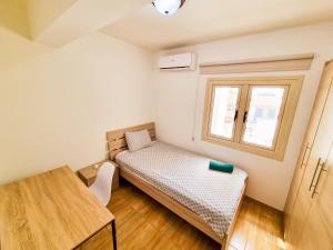 Una pequeña habitación con una cama y una ventana. en Sunbay City Rooms, en Lárnaca