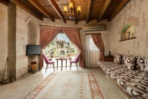 Una sala de estar con un sofá y sillas y un televisor. en Doors Of Cappadocia Special Cave Hotel, en Göreme