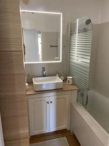 La salle de bains est pourvue d'un lavabo, d'un miroir et d'une baignoire. dans l'établissement Saint Tropez Spacieux Appartement La Florida, à Saint-Tropez