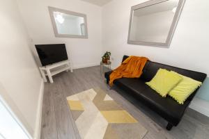 a living room with a black couch and a tv at Bright and spacious contractor house!Free WiFi! in Luton