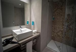a bathroom with a sink and a mirror and a shower at Hotel Don Juan Tossa in Tossa de Mar