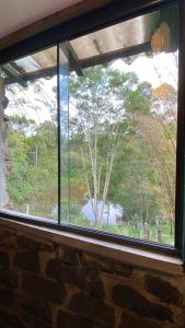 una ventana en una pared de ladrillo con vistas a los árboles en Pousada dos Anjos, en Cunha