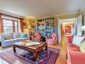 a living room with a coffee table and bookshelves at Tuffon Hall Farmhouse in Halstead