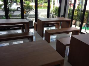 a group of tables and benches in a room with windows at Bird Day Boutique Hotel in Mukdahan