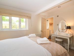 ein weißes Schlafzimmer mit einem Bett und einem Spiegel in der Unterkunft White Stones in Burford