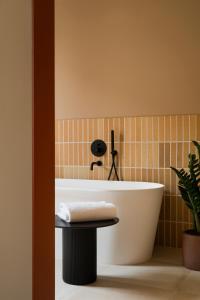 La salle de bains est pourvue d'une baignoire blanche et d'une plante. dans l'établissement CASA Y FONDA 1888, à Alcalá de Henares