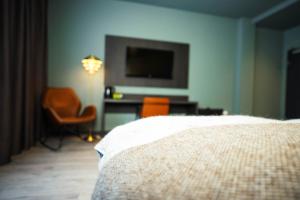 a bedroom with a bed and a tv and a chair at Konvin Hotel by Reykjavik Keflavik Airport in Keflavík
