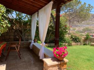 a patio with a canopy and a table and flowers at Studios Irene in Skala