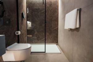 a bathroom with a toilet and a glass shower at Konvin Hotel by Reykjavik Keflavik Airport in Keflavík