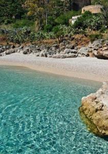 a beach with clear blue water and a rocky shore at Stella marina in Castellammare del Golfo