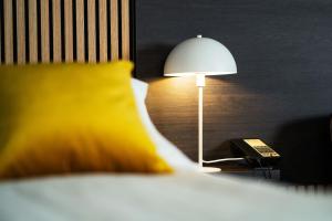 a lamp sitting on a night stand next to a bed at Konvin Hotel by Reykjavik Keflavik Airport in Keflavík