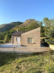 a brick house with a hill in the background at Terra del Sasso Country-house in Sasso di Castalda