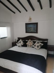 ein Schlafzimmer mit einem großen Bett mit schwarzen und weißen Kissen in der Unterkunft Beraka Boutique in Villa de Leyva