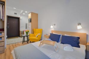 a bedroom with a large bed and a yellow chair at Cosy and Stylish Studio next to Sofia's Central Market Hall in Sofia