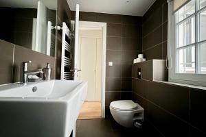 a bathroom with a white sink and a toilet at Louvre Penthouse PadATerre Owner Direct since 1999 in Paris