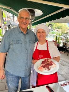 un hombre mayor y una mujer sosteniendo un plato de pizza en Stephen Center B&B, en Tirana