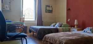een kamer met 2 bedden, een stoel en een raam bij Chambre chez l'habitante "Bambou" in Derval