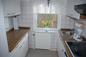 a kitchen with a vase with yellow flowers in a window at Ferienwohnung Jepsen in Glücksburg +9 photos