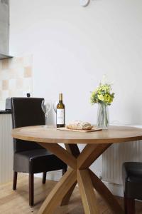 een houten tafel met een fles wijn en een vaas met bloemen bij Chiff Chaff in Belford