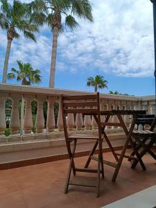 a wooden bench sitting on a balcony with palm trees at Bon Repos - B10, Apartamento con Terraza en Cala'n Bosch in Cala en Bosc