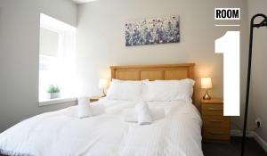 um quarto com uma cama branca e um quadro na parede em Rooms on the High Street em Portree