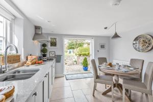 a kitchen with a sink and a table with chairs at Coombe Cottage in Dorchester