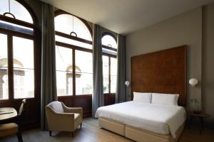 Schlafzimmer mit einem Bett, einem Stuhl und Fenstern in der Unterkunft Hotel Dei Dragomanni in Venedig