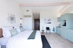 a bedroom with a white bed and a kitchen at Terre d'Orizon in Tourrettes-sur-Loup