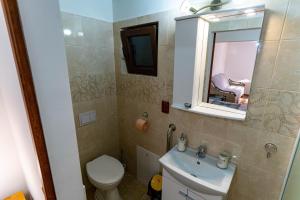 a bathroom with a toilet and a sink and a mirror at La Bebe 2 Beds in Hunedoara