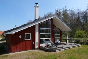 une cabine rouge avec deux chaises et une table sur une terrasse dans l'établissement Resort 2 Ocean Cottage A 87, à Großenbrode