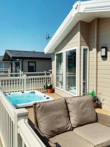 a couch sitting on a deck next to a hot tub at Heathery Lodge with Hot Tub in York