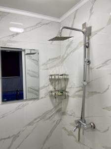 a white bathroom with a shower and a mirror at Comfortplace in Atyraū
