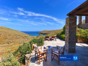 un patio con sillas, una mesa y el océano en Agelos Beachfront Villa, en Korissia