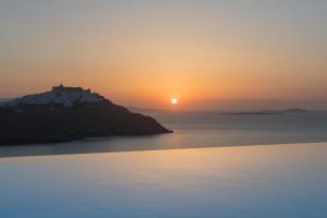 - un coucher de soleil sur l'océan avec un château sur une colline dans l'établissement Nisides Suites, à Livadi Astypalaias