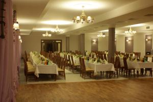 un salón de banquetes con mesas y sillas blancas y lámparas de araña en Hotel Stary Młyn, en Suchedniów