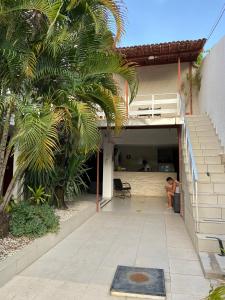 une femme assise sur une chaise devant une maison dans l'établissement Pousada Nossa Casa, à Maceió