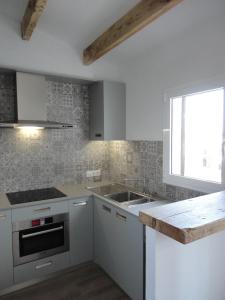 a kitchen with white cabinets and a sink and a window at Sol del Este in Es Castell