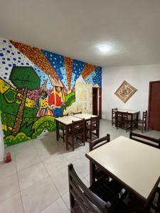 un restaurant avec des tables et une fresque murale. dans l'établissement Pousada Nossa Casa, à Maceió