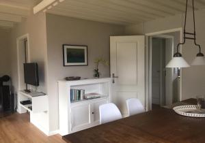 ein Wohnzimmer mit einem Bücherregal und weißen Stühlen in der Unterkunft Ferienhaus Andersen Ferienhaus Andersens Hus in Böhl